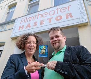Sibylle Kühn vom Forum am Dom und Moderator Urs von Wulfen präsentieren den Osnabrücker Löwenpudel, der beim vierten Prediger-Wettbewerb am 20. September im Osnabrücker Hasetor-Kino zu gewinnen ist.